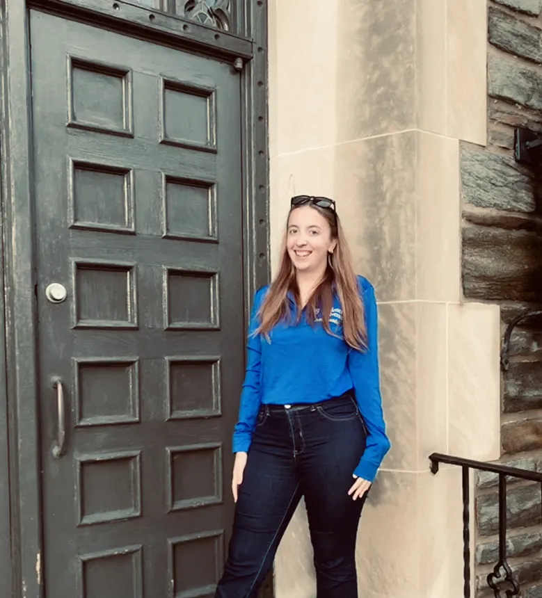 Zoe Sweet stands in front of a large green door.
