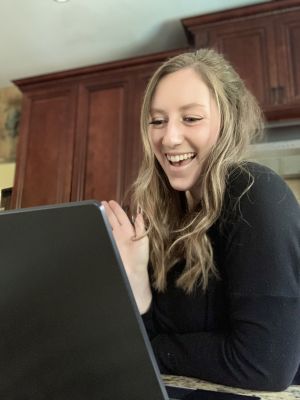 Graduate student waves in front of laptop