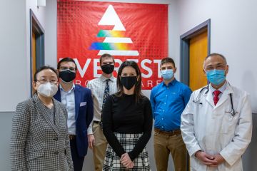 6 people stand in front of a red banner that says Everest Urgent Care