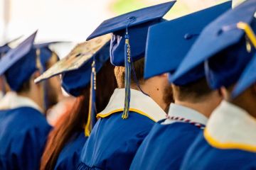 Graduates taken from behind at commencement, with 2024 tassels
