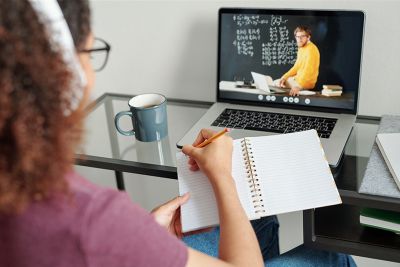 student with notebook in front of laptop