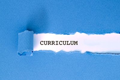 Blue sheet with a tear pulled back to reveal the word 'curriculum'