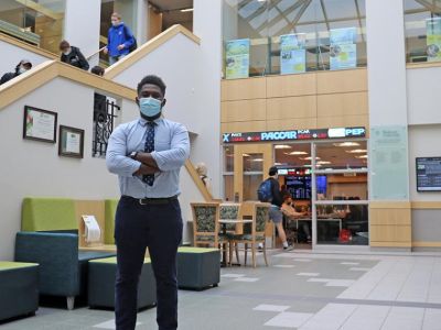 Brandon Matambo stands with his arms crossed in the Quick Center atrium.