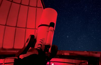 a person looks through a large telescope at the Widener University Observatory