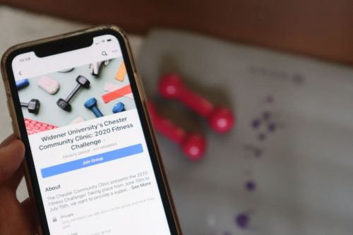 Cell phone shows fitness challenge with weights in background