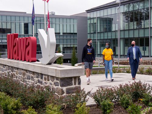 Two students and alum walking at Wawa headquarters