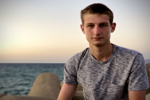 Greek international student Thanos Tziatzioulis standing in front of the sea