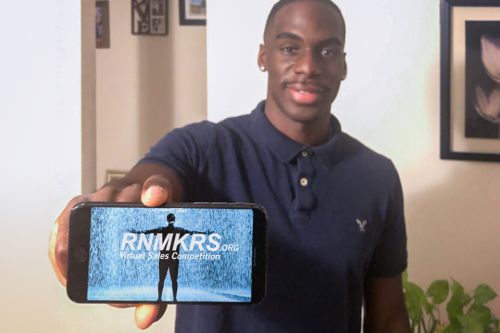 Student holds out phone displaying RNMKRS sales competition logo