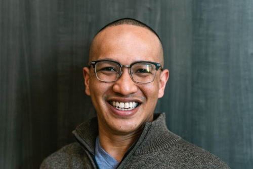 Alumnus Patton Vo, class of 2015, wearing a blue T-shirt and gray zip-up pullover