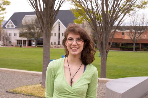 Widener class of 2024 student Catherine "Catie" Sengstock in front of Memorial Field. She is wearing a green shirt and a small necklace.